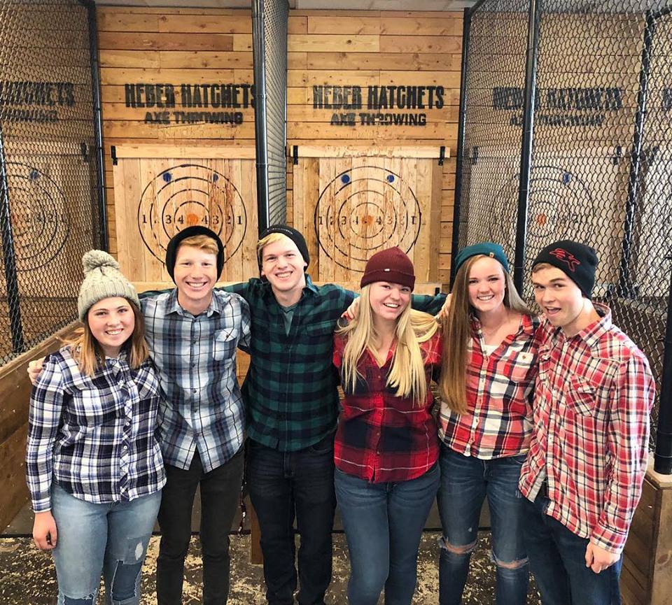 a group of young people on an axe throwing date wearing flannel 