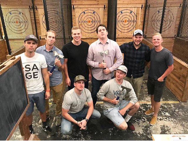 a group of men pose with axes during a bachelor party