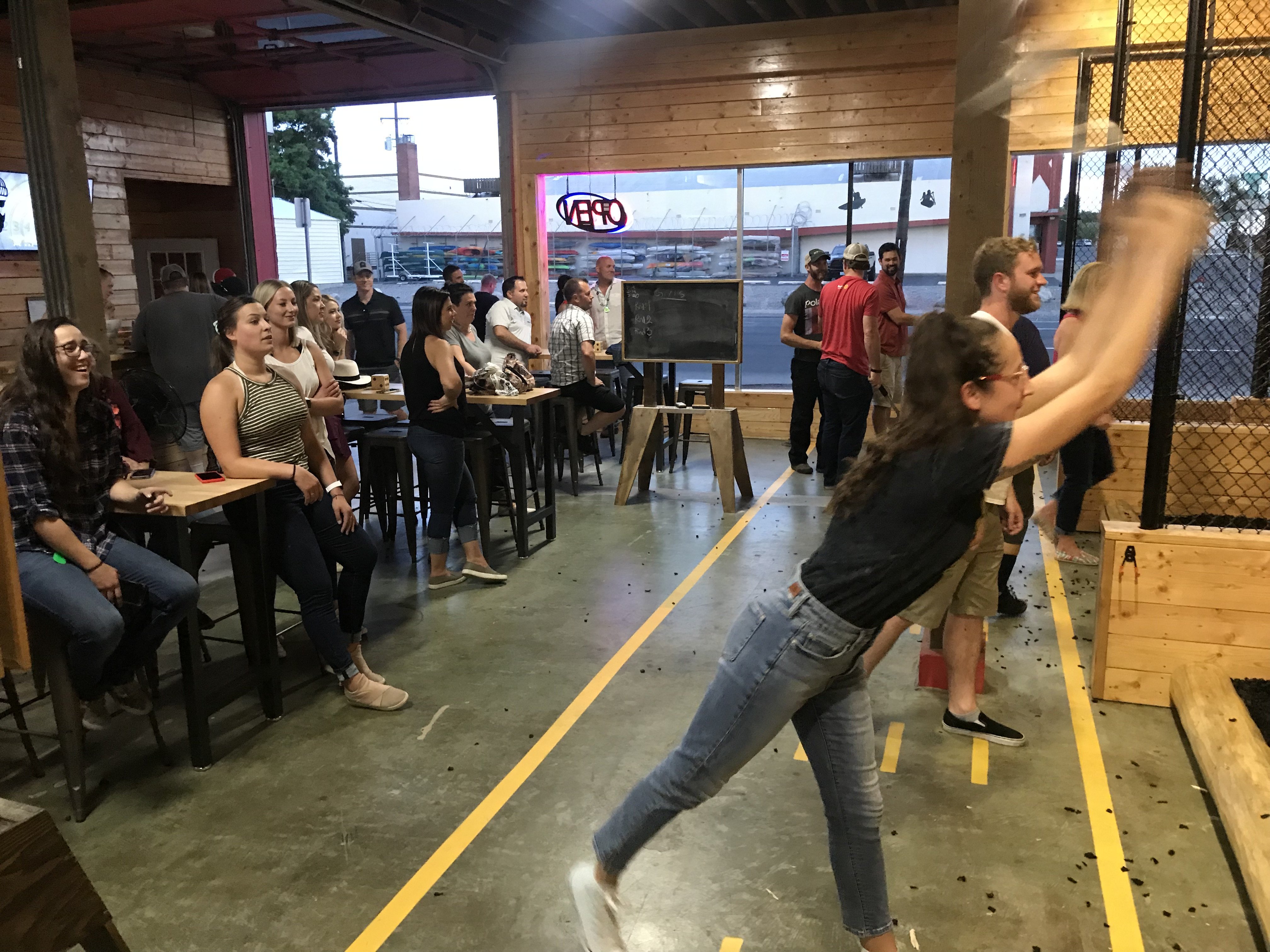 a large group enjoys axe throwing games at Heber Hatchets in Spokane