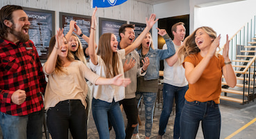 A group of college students celebrate during an axe throwing game