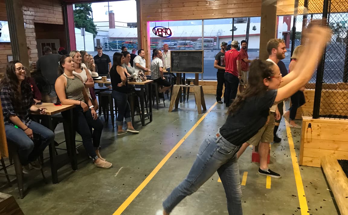 a large group enjoys axe throwing games at Heber Hatchets in Spokane